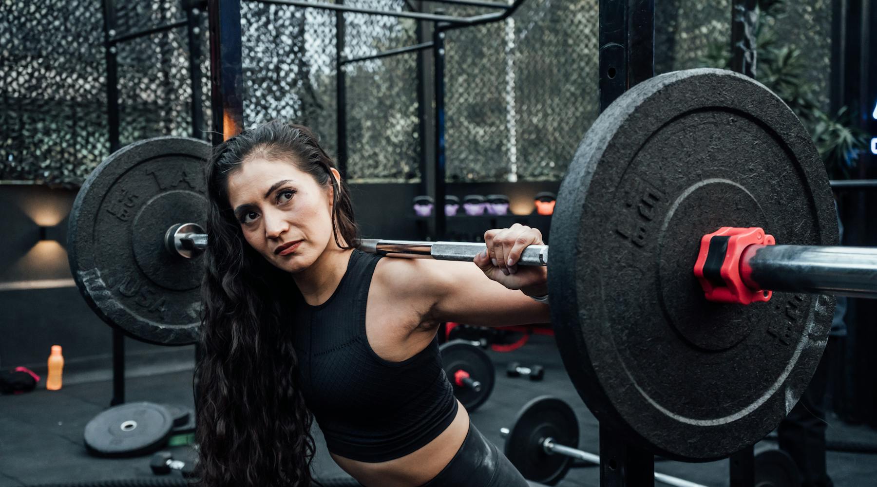 A determined woman lifting weights in a modern gym, embodying fitness and strength.